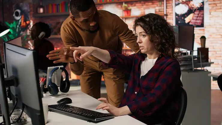 Unity Game Development Agency in Canada Supervisor checking on IT expert using artificial intelligence in a modern office.